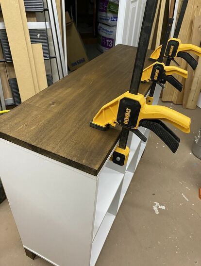 With this easy project you can make a cheap, boring cube storage shelf look like a modern piece of furniture.    Measure and prepare wood    First I purchased a piece of 3/4 inch poplar plywood and used the table saw to cut it down to match the exact dimensions of the top of the cabinet. Then I used 1.5"x2" pieces of pine leftover from a previous project for the four legs. I cut them down to a height of 3" each using the miter saw. You can cut pine 2"x4"s down to the size you need for… Diy Cube Storage, Ikea Cubes, Cheap Ring, Shelf Makeover, Cube Storage Shelves, Poplar Plywood, Cube Shelves, Cube Organizer, Wood Bookcase