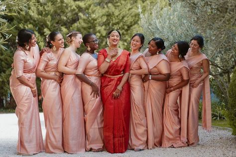 Bridal party with bride in a red lehenga and pink bridesmaids dresses Red Saree Bride With Bridesmaid, Indian Bridesmaids Saree Outfits, Sari Bridesmaid Dress, Indian Bridesmaid Gifts, Telugu Bridesmaids Outfits, Pink Bridesmaid Saree, Indian Wedding Theme Colors, Bridesmaid In Saree, Tamil Wedding Bridesmaid