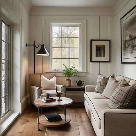 A cozy cottage living room with cream paneled walls, cream sofa, plaid throw pillows, accent chair, round metal and wood coffee table, black English floor lamp, small English cottage living, vintage wall art, and oak wood flooring.   Design: @windthekey  Follow @windthekey for more design inspiration. Living Room New England Style, Cottage Living Room Windows, Built In Sunroom, Apartment Farmhouse Living Room, Cream Cottage Living Room, Small Space Vintage Decor, Cozy Cottage Decor English Country, Modern Cottage Furniture, Small Living Room Sofa And Chair