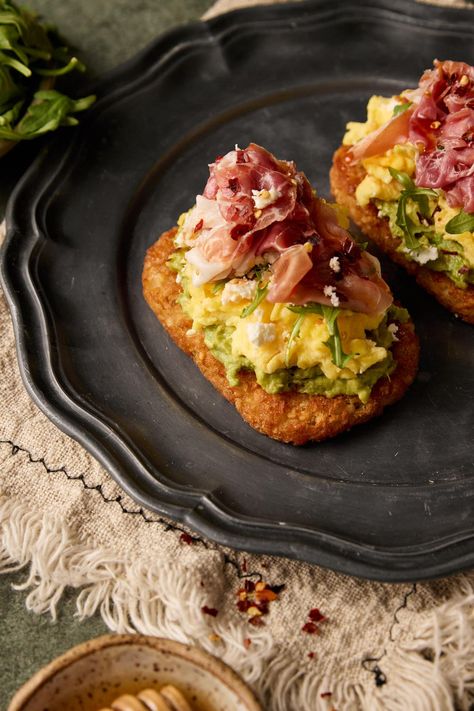 Introducing my Hashbrown Avocado Toast with Prosciutto—a delicious and satisfying breakfast or brunch option. This dish combines crispy hashbrowns, creamy avocado, prosciutto, arugula, and crumbled feta, all perfectly complemented by a drizzle of honey Brunch Items Easy, Eggs And Prosciutto Breakfast, Breakfast Guacamole Toast, Breakfast Prosciutto Recipes, Brunch Board Ideas For Two, Avocado Toast On Hashbrown, Brunch Hashbrown Ideas, Hashbrown Skillet Breakfast, Delicious Brunch Ideas