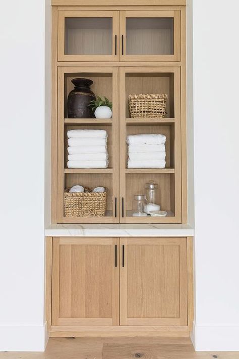 Built in tan wooden bath linen cabinet boasts glass doors. Built In Tv Cabinet, Bathroom Linen Closet, Pure Salt Interiors, Light Wooden Floor, Cabinets With Glass Doors, Built In Bath, Pure Salt, White Shiplap Wall, Built In Cabinet