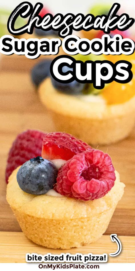 Close up of a sugar cookie cup full of cheesecake filling and topped with fruit with title text overlay Fruit Pizza Cookie Cups, Fruit Pizza Sugar Cookie Cups, Individual Fruit Pizza Cookies, Fruit Pizza Cups Mini, Dessert For A Cookout, Sugar Cookie Cheesecake Cups, Cookie Cup Desserts, Sugar Cookie Cups Muffin Tin, Cookie Fruit Cups