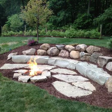 Backyard Fire Pit Ideas | Hunker Fire Pit With Rocks, Outdoor Fire Pit Area, Sunken Fire Pits, Brick Fire Pit, Backyard Fire Pit, Rustic Fire Pits, Fire Pit Landscaping, Sloped Backyard, Cool Fire Pits