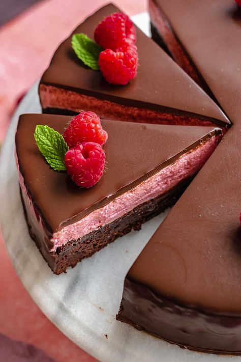 This layered raspberry mousse cake has a chewy chocolate brownie cake layer, light and fresh raspberry mousse, and gets covered in a glossy dark chocolate ganache. It's the perfect cake for Valentine's Day or a special gathering and is sure to please a crowd! Raspberry Brownie, Layered Mousse Desserts, Raspberry Topping, Dark Chocolate Raspberry Brownies, Advanced Desserts, Chocolate Cake With Raspberries, Raspberry Chocolate Torte, Chocolate Decadent Desserts, Raspberry Mouse For Cake