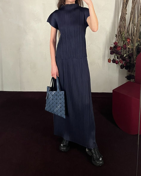 Featured here are the high-neck pleated top and voluminous pleated skirt in navy by Pleats Please. Tülay styles with the dark blue prism matte tote bag from Bao Bao Issey Miyake.⁠ Pleats Outfit, Pleats Top, Issey Miyake Pleats Please, Pleats Skirt, Bao Bao Issey Miyake, Bao Bao, Pleats Please, Pleated Top, Grown Women