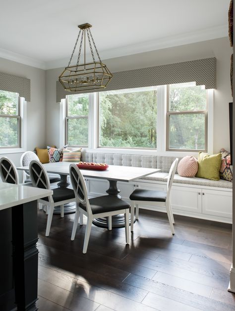 This beautiful breakfast nook came together with the white upholstered dining chairs and adorable grey window bench. The storage under the window seat is a great addition to this dining area. The throw pillows on the window seat add a pop of color and pattern and the large dining room light fixture centers the focus of the room. #colorfuldiningroom #colorfulthrowpillow #windowbench #diningwindowseat #africanpattern Dining Room Window Bench Seating, Bench Seating Under Window Dining Room, Dining Room With Window Bench, Banquette Seating Under Window, Bench Under Window Dining Room, Window Nook Dining Room, Bench Seating Kitchen Window, Under Window Banquette, Dining Room Built In Bench Under Window