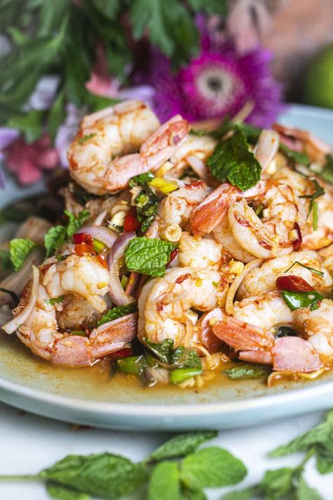 Need a tasty idea for a quick lunch? Try Pla Goong, a spicy Thai shrimp salad full of flavor. It has fresh herbs, big juicy shrimp, and spicy Thai chili peppers. The dressing is tangy and spicy too. Give your taste buds a treat with this yummy salad you'll want to eat again and again! #plagoongrecipe #plagoongingredients #plagoongsaladrecipe #thaishrimpsalad #spicythaishrimpsalad #prawnsaladthai #plagoongsalad Spicy Crab Salad, Spicy Thai Shrimp, Spicy Shrimp Salad, Thai Chili Peppers, Thai Shrimp Salad, Thai Salad Recipes, Green Mango Salad, Prawn Salad, Thai Shrimp