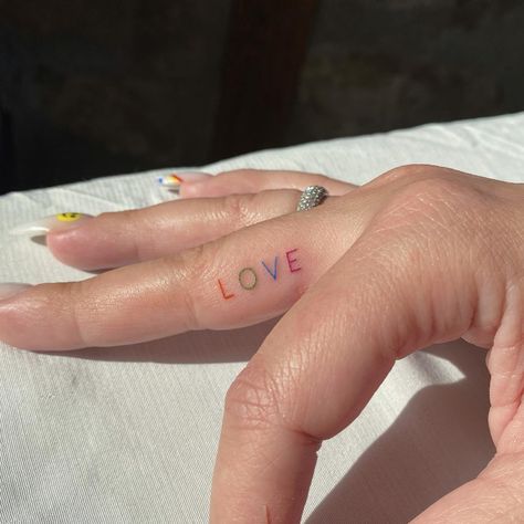 Colorful Finger Tattoo, Tattoo Minimal Color, Pride Finger Tattoo, Rainbow Letter Tattoo, Finger Tattoos Colorful, Tiny Colourful Tattoos, Tiny Pride Tattoos, Inner Finger Tattoos For Women, Inner Finger Tattoos Words