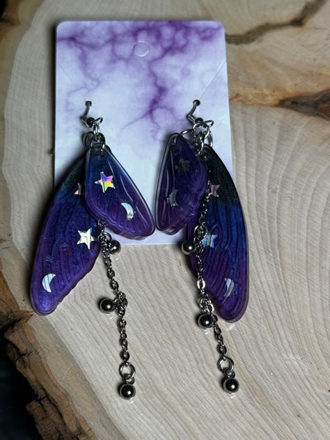 These Dark Purple Magic Chain Double Fairy Wings are amazing earrings for yourself or someone else as a gift! The Earring hooks are made of 925 sterling silver and earring backs are made of clear silicone.  Earrings are handmade which makes every piece a unique piece of art.   Earring size from hook to bottom of chain: 3.5" Fairy Wing Size: 2" (1) Earring Weight: 3.5 oz.   Do not leave in a hot car. Handle with care. BatCravt is not responsible for any damage after shipping.  No returns or exchanges accepted. Emerald Green Accessories, Outfit Ideas Purple, Fairy Wing Earrings, Magic Purple, Car Handle, Amazing Earrings, Purple Magic, Glitzy Glam, Magic Fairy