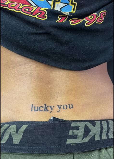 Lucky U Tattoo, Tramp Tattoos For Women, Stamp Tramp Tattoo Lower Backs, Trap Stamp Tattoos Black Women, Lower Back Tattoos For Women Words, Lower Back Tattoo Black Women, Funny Word Tattoos, Trampstamp Tattoo Words, Back Stamp Tattoo