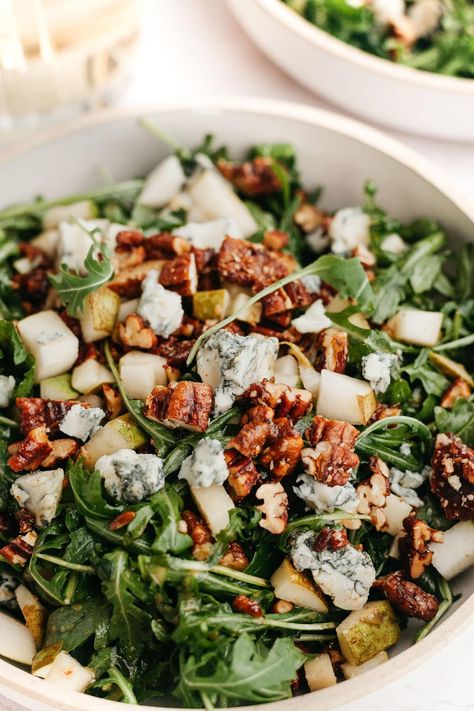 This delicious salad includes peppery arugula, sweet pears, creamy crumbled gorgonzola or blue cheese, and candied pecans. Toss it all in a simple homemade dressing and enjoy! Arugula Salad Thanksgiving, Arugula Blue Cheese Salad, Holiday Arugula Salad, Thanksgiving Salad Arugula, Roasted Pecans For Salad, Arugula Pecan Salad, Dressed Greens Salad, Arugula Balsamic Salad, Gorgonzola Pear Salad