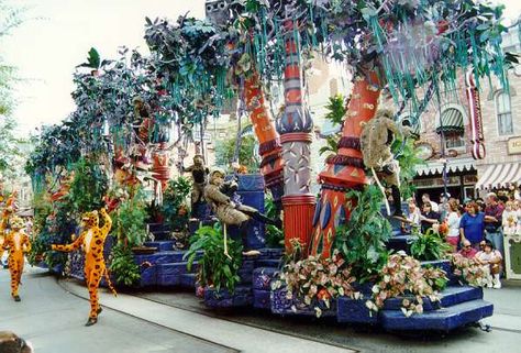 Rainforest Unit represents Simba's "Hakuna Matata," or carefree, days in the rain forest- The wooden flowers and various jungle bugs for both this and the Bull Elephant float were designed and created in the country of Bali especially for this parade. The colorful tree trunks are textured with a circular looping pattern, recognized as the worldwide symbol for infinity, and representing the circle of life. Lion King Celebration parade, Disneyland Bull Elephant, Lion King Jr, Derby Ideas, Tree Trunks, Colorful Trees, Wooden Flowers, Circle Of Life, Lion King, Animal Kingdom