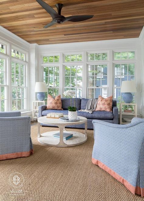 A matte black modern ceiling fan is mounted in a sunroom to a wood plank ceiling over a round gray wash wooden coffee table placed on a sisal rug. Southern Sunroom, Sunroom Ceiling Ideas, Black Modern Ceiling Fan, Traditional Sunroom, Round Rug Living Room, Small Sunroom, Wood Plank Ceiling, 3 Season Room, 4 Season Room