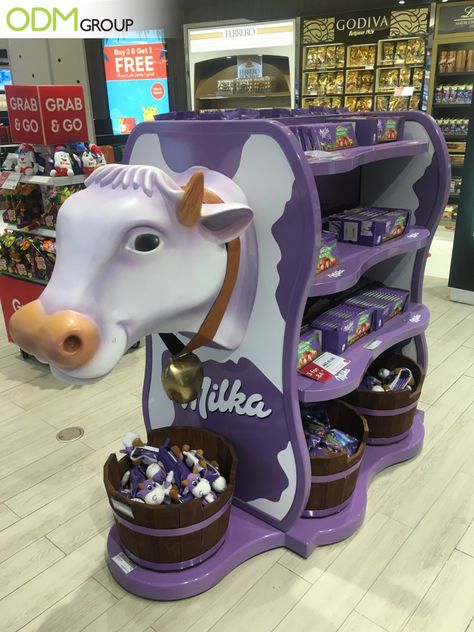 What brand comes to mind when you see a purple cow display inside the store? We automatically associate it with the chocolate brand Milka, correct? One of our staff members has recently come across their retail marketing display at a Duty-Free shop. The signature purple display is a head-turner! #POS #display #unique #eyecatching #catchy #design Milk Display, Retail Display Design, Toy Shop Display, Supermarket Display, Duty Free Shop, Shopper Marketing, Retail Design Display, Grocery Store Design, Retail Marketing