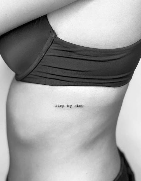 Tattoo Ideas On Ribs Quote, Stepping Into A New Me Tattoo, Text Tattoo Side Rib Women, Writing On Ribs Tattoo Women, Small Tattoos On Rib Cage, One Line Rib Tattoo, One Word Rib Tattoo, Rib Cage Script Tattoo, Dainty Rib Cage Tattoos