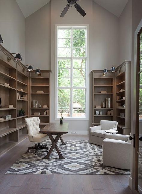 Amazing home office features a tall vaulted ceiling adorned with a ceiling fan over brown stained tall bookcases illuminated by black and gold swing-arm sconces. High Ceiling Office, Office Built Ins, Georgia Homes, Meteor Garden 2018, Tall Ceilings, Transitional House, Small Home Office, Country French, New Home Builders