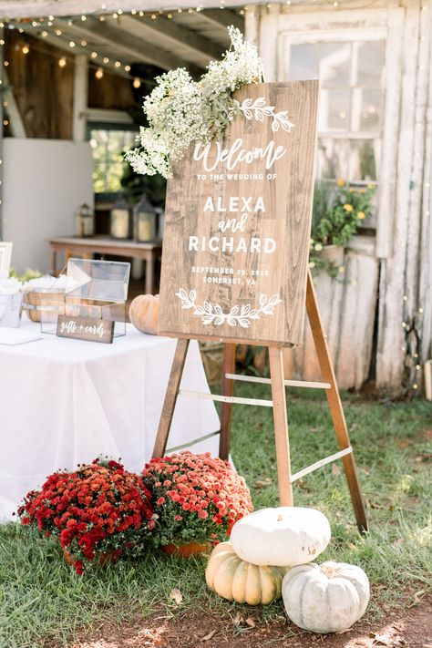 This autumnal welcome sign is adorned with a floral swag of baby's breath and seeded eucalyptus with mums and ornamental pumpkins at the base for a seasonal touch. Photographer Shannon Moffit. White Pumpkins And Eucalyptus Wedding, Mums Ceremony Decor, White Mum Wedding Decor, Entryway Wedding Decor Receptions, Mums And Pumpkins Wedding, Wedding Welcome Sign Baby Breath, Mums At Wedding Ceremony, Fall Wedding Mums And Pumpkins, Wedding Mums Decor