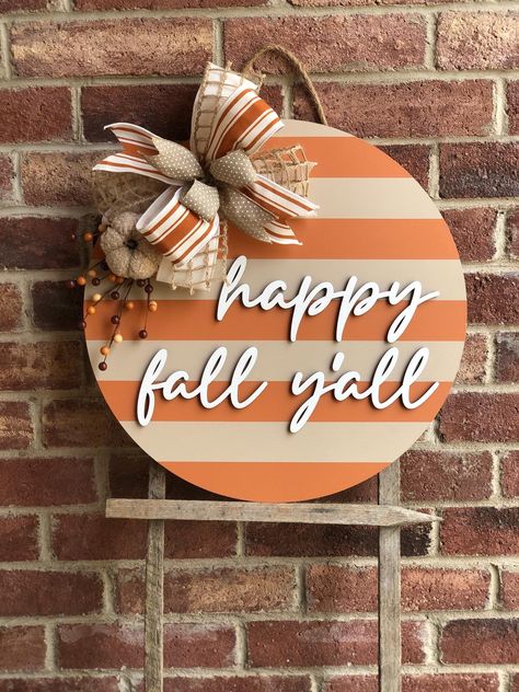 We offer a wide variety of wooden door hangers to spruce up your front door!  Fall Front Door Decor, Happy Fall Y'all Door Hanger, 3D Lettering, Happy Fall Wreath, Fall Porch Decor, Fall Decor Outdoor, Wooden Fall Sign FALL DOOR HANGER DETAILS Size: 18 inches OR 22 inches;  1/2 inch thick Includes faux fall picks arrangement and bow 3D laser cut lettering Back is unfinished These make the perfect gift for a loved one! Whether it be a housewarming gift, wedding gift, client gift, or just for your Front Door Fall Signs, Fall Wooden Door Signs, Round Fall Door Signs, Fall Front Door Sign, Fall Wood Door Hangers, Popular Diy Crafts To Sell, Simple Fall Door Hangers, Fall Front Door Signs, Diy Fall Door Hangers