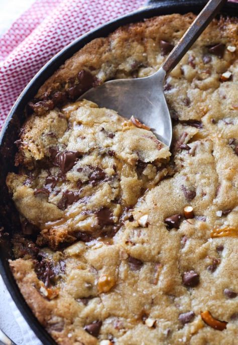 This Salted Caramel Pizookie is over the top delicious! A buttery chocolate chip cookie loaded with salted pretzels with a creamy caramel filling all baked in a skillet! Ooey gooey salted caramel deliciousness! #cookiesandcups #pizookie #castironskillet #skilletrecipe #skilletcookie #saltedcaramel Cookie In A Skillet, Pizookie Recipe, Buttery Chocolate Chip Cookies, Cast Iron Skillet Recipes Dinner, Skillet Cookie Recipe, Skillet Desserts, Salted Caramel Cookies, Skillet Chocolate Chip Cookie, Caramel Filling