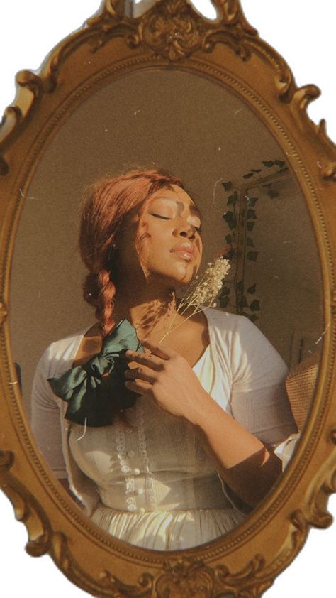 A beautiful black woman in a gold vintage mirror with her eyes closed holding a piece of baby’s breath. Her hair is in a braid with a green bow. Cottagecore Poc Women, Poc Cottagecore Aesthetic, Cottagecore Person, Cottagecore Lesbian Aestethics, Scottish Farm, Hyperfeminine Aesthetic, Poc Cottagecore, Black Feminity, Black Girls With Freckles