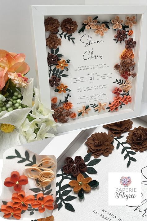 White shadow box displaying a fall wedding invitation keepsake made of fall colored paper flowers that mimic the wedding flowers. There are simple five petal flowers of varying fall colors and many have beads attached to the centers. Machine cut hand formed flowers and leaves are also included and they all surround the wedding invitation beautifully.. Quilled Wedding Invitations, Wedding Memory Box Ideas, Terracotta Fall Wedding, Wedding Quilling, Quilling Wedding, Wedding Invitation Keepsake, Quilling Wall Art, Wedding Memory Box, Wedding Gift For Couple