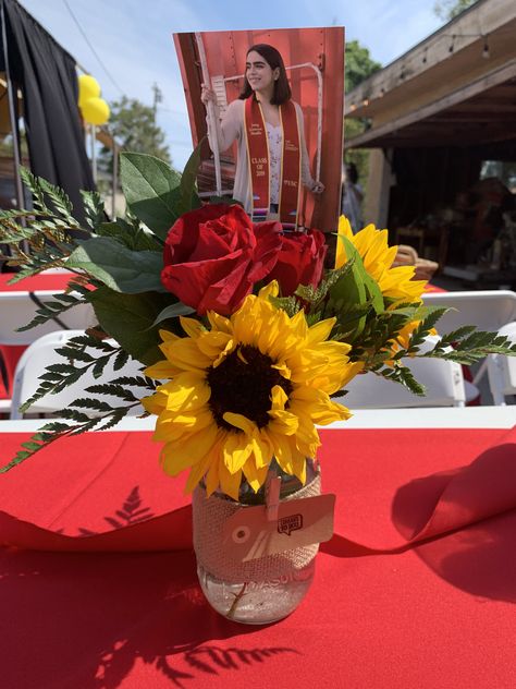 Mason jar . Mason jar with sunflowers , red carnations and red roses . Mason jar centerpiece . Fresh flowers . Burlap wrapped around the mason jar . USC colors red and yellow . Best part to add a picture of the celebrated graduate . Cute and super simple Graduation Party Centerpieces Mason Jars, Yellow Party Decorations, Floral Graduation Party, Red Centerpieces, Senior Graduation Party, Graduation Flowers, Mason Jar Centerpiece, Sunflower Party, Graduation Party Diy