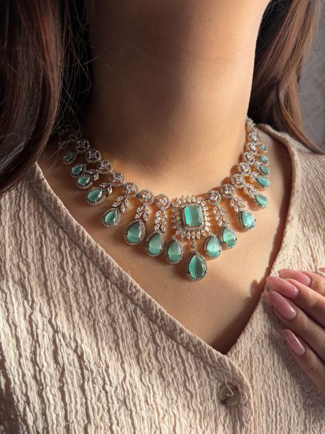 Add a touch of elegance and sophistication with this gold  finish necklace set in beautiful mint green stones. The stones in this set bling and look close to the real thing. This set is sure to make heads turn!  It features an adjustable necklace and a pair of earrings. It can be paired perfectly with both ethnic and western outfits.  In case of any queries, please feel free to reach out. Happy shopping!   Length: 15 inches with an adjustable high quality metal chain at the back Earrings length: 2.5 inches Each earring weighs 15 gms  Closure: Pushback Earrings Closure: Pushback Necklace Closure: Hook Wedding Jewellery Necklace, American Diamond, Adjustable Necklace, Green Stone, Western Outfits, Metal Chain, Green And Gold, Gold Finish, Necklace Set