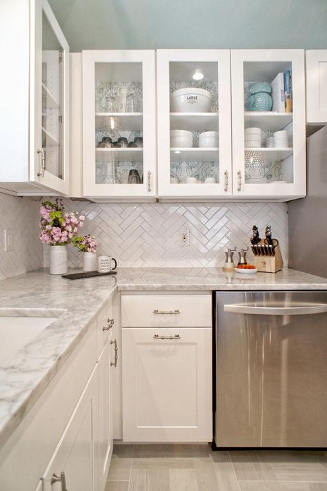 This light and bright modern kitchen combines white and gray tones to create a lively area of the home. Glass front cabinets are mixed in with white Shaker style cabinets, while a gray and white marble countertop offers a finishing touch. A white tile herringbone backsplash adds fun texture to the space. Kitchen With White Cabinets, Shoes Organizer, Kitchen Ikea, Organizer Ideas, Kabinet Dapur, Herringbone Backsplash, Decor Ikea, Classic Kitchen, White Kitchen Design