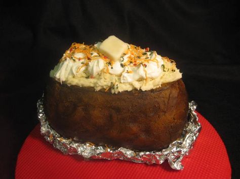 Baked Potato Cake - I took a half sheet cake and cut it into 3 pieces and stacked it together.Then I  carved it to look the shape of a potato.  Frosted in with buttercream and airbrused it yellow, then orange, then brown. I took some cake crumbs and mixed it with buttercream for the potatoes on top. I then placed drops of buttercream on top for sourcream. I took green tinted coconut       sprinkled it on top for chives. I made the bacon bits, cheese and butter out of modeling chocolate. Potato Shaped Cake, Impressive Food, Half Sheet Cake, Brown I, Cake Shapes, Potato Cakes, Modeling Chocolate, A Potato, Home Bakery