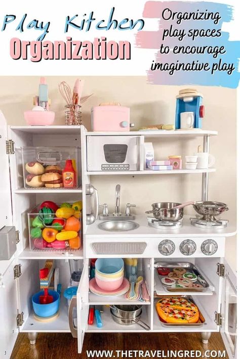 PLAY KITCHEN ORGANIZATION TO ENCOURAGE IMAGINATIVE & PRETEND PLAY by The Traveling Red Play Kitchen Small Space, Play Kitchen Must Haves, Playroom Kitchen Organization, Play Kitchen In Kitchen, Toddler Kitchen Accessories, Pretend Play Organization, Toy Kitchen Storage Ideas, Pretend Play Playroom Ideas, Play Kitchen In The Kitchen