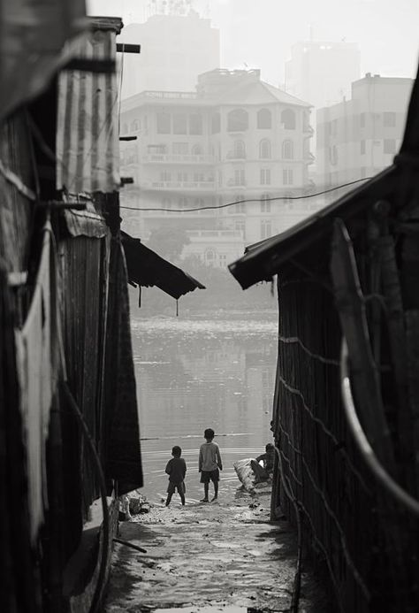 Fred Grille - Children looking from the slum on their wealthy neighbors. The Koreil slum in Dhaka, Bangladesh is the largest slum in the capital city and is home to more than 40.000 people. Just on the other side of the small lake is the wealthy neighborhood Gulshan. Mumbai Slum Photography, Manila Slums, Slums Aesthetic, Wealthy Neighborhood, Poverty Photography, Slum Area, Bay Of Bengal, Alfred Stieglitz, Small Lake