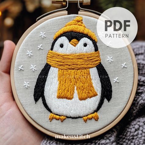 Stitch your own cuddly piece of decor with this charming penguin embroidery design! This PDF pattern features an adorable penguin bundled up in a cozy yellow scarf and hat, perfect for adding a pop of cheer to any space. The simple yet expressive design captures the penguin's sweet personality, while delicate snowflake stitches add a magical winter touch.  YOUR DOWNLOAD INCLUDES: * Printable pattern scaled to fit 4" to 8" hoops * Beginner's Embroidery Guide * The Guide includes step-by-step phot Penguins Christmas Decorations, Nativity Embroidery, Penguin Embroidery, Embroidery Christmas Gifts, Embroidery Ornament, Embroidery Designs Cute, Sweet Personality, Ornament Embroidery, Winter Penguin