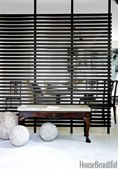 LOUVERED SCREEN – In a retro Houston home, Elizabeth Kennedy and Ray Booth replaced the '60s room divider with a sleek alternative. An antique bench sits against a custom partition, painted in Benjamin Moore's Briarwood. Click through for the entire gallery and for more entryway ideas. Tension Room Divider, Office Space Divider Ideas, Garage Room Divider Ideas, Office Divider Ideas Open Spaces, Industrial Room Divider, Room Dividers Ideas, Dividers Ideas, Slatted Wall, Bedroom Divider