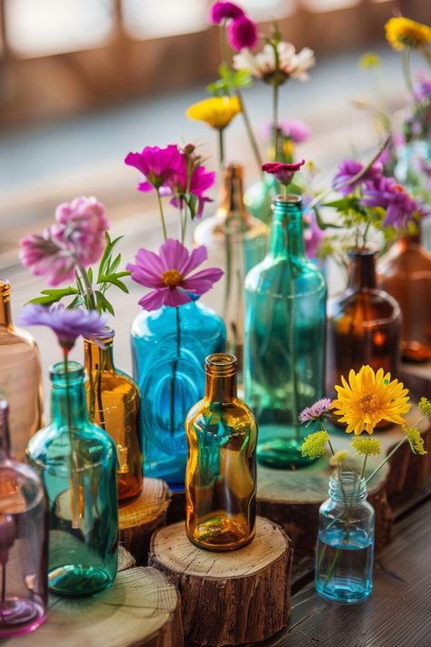 Capture the essence of bohemian elegance on your special day 🌸. These simple yet stunning wedding table centerpieces combine rustic wood slices and vibrant glass bottles for a unique touch. Perfect for couples who love a pop of color and natural beauty in their decor. #BohoWedding #WeddingInspiration #CenterpieceIdeas #WeddingDecor #DIYWedding #RusticChic #FloralDecor #WeddingDetails Colored Glass Centerpiece Wedding, Wildflower Wedding Table Decor, Bohemian Wedding Table Decor, Driftwood Wedding Centerpieces, Unique Table Centerpieces, Colorful Table Decor, Driftwood Wedding, Boho Cowboy, Boho Wedding Centerpieces