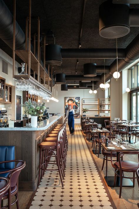 Bistro Le Bleu in Aarhus, Denmark has an airy and light interior design with large windows and a high ceiling. To ensure the bistro’s good acoustic qualities, black Troldtekt acoustic panels were chosen for the entire ceiling to camouflage the black-painted ventilation pipes and similar installations. #goodacoustics #holzwolleplatten #träullsplattor #woodwoolpanels #troldtekt | Architects: SLETH High Ceiling Cafe Design, Brasserie Design Interior, Pizzeria Interior Design Ideas, Exposed Ceiling Design Restaurant, Modern Bistro Interior Design, Large Cafe Interior, Bistro Interior Design Ideas, Bistro Design Interior, Low Ceiling Restaurant