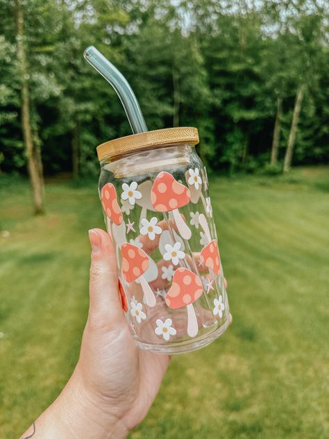 This trendy glass is the perfect vibe for the warmer weather! The glass pictured below is 16oz. All of our cups are made with permanent uv decals and come with a bamboo lid & reusable glass straw. All glasses are handwash only and come with care instructions in each package! This item is made to order and is not eligible for return. If you have any questions about your order, please reach out to us at bidwellbydesign@gmail.com. Pretty Glass Cups, Glass Bottle Design Ideas, Custom Cups Ideas, Mushroom Glass Cup, Glass Cups With Bamboo Lids Designs, Cute Glass Cup Designs, Glass Water Bottle Aesthetic, Cricut Glass Cups, Cute Glass Cups