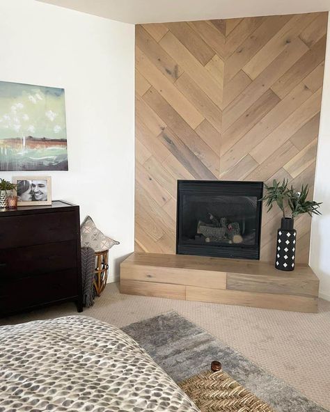 Wood-look shiplap in a herringbone pattern with an inset black fireplace creates an eye-catching feature wall. A patterned black and white vase sits on the wooden tile hearth. Wood Tile Wall Accent, Chevron Wood Fireplace Wall, Vertical Shiplap Fireplace Wall, Herringbone Fireplace Surround, Herringbone Shiplap, Tile Hearth, Herringbone Fireplace, Fireplace Accent Walls, Inset Fireplace