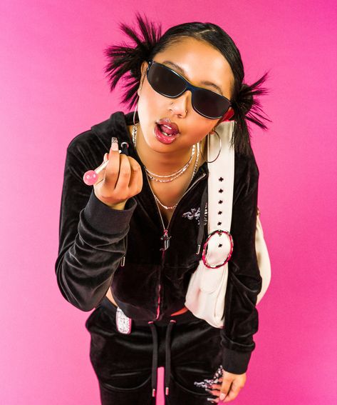 Girl standing in front of a pink backdrop leaning slightly forward, she has a sassy facial expression and is pointing at the camera holding a lollipop. She is wearing a black juicy couture tracksuit set, sunglasses and has a white shoulder bag over her left arm. The shoot is a y2k early 2000s look. 2000s Fashion Editorial, Y2k Aesthetic Women, 2000s Ads Fashion, Y2k Model Photoshoot, Early 200s Photoshoot, Y2k Fashion Editorial, Trashy Y2k Photoshoot, Y2k Fashion Shoot, Y2k Concept Photoshoot