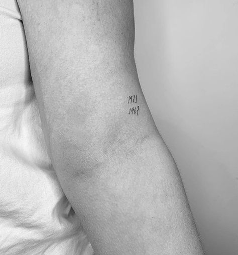 Above Back Of Elbow Tattoo, Minimalist Grandparents Tattoo, Simple Birth Year Tattoo, Year Dates Tattoo, Tiny Birthday Tattoos, Delicate Date Tattoo, Fine Line Year Tattoos, Creative Number Tattoo, Small Tattoos Parents