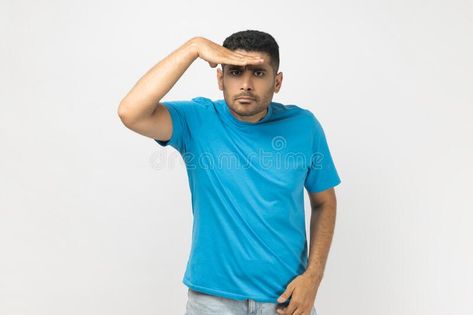 Man keeps hand near forehead looks far away, searches something on horizon. stock photography Hand On Forehead, Hunter Gatherer, Vector Banner, Men Looks, Blue Tshirt, Pose Reference, Stock Photography, Acting, Photo Image