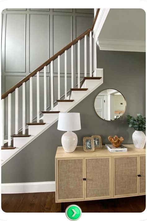 Two-toned green and white staircase wall featuring a circular mirror enhances space and light. The soft green blends beautifully with white paneling for a refreshing and airy feel. Accent Wall Stairs Staircases, Foyer With Staircase, 2 Story Staircase Wall Decor, Staircase Wall Paint, Entryway Molding Ideas, Dark Green Staircase Wall, Entry Hall Accent Wall, Walled In Staircase, Accent Wall Entryway Foyers