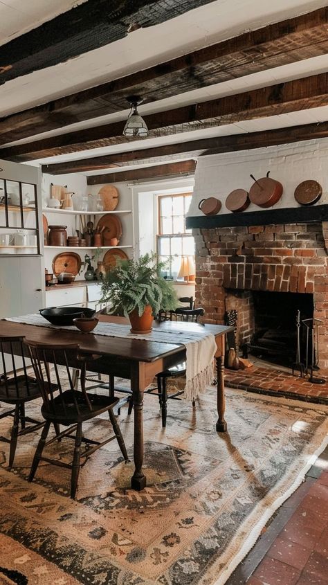 Cozy kitchen with exposed beams, brick fireplace, wooden dining table, and copper pots. Rustic and inviting space perfect for family gatherings. Brick Fireplace In Kitchen, Dining Room With Brick Fireplace, Fireplace In Dining Room, Fireplace Dining Room, Kitchen Hearth, Dining Room With Fireplace, Country Style Dining Room, Fireplace Dining, Red Brick Fireplaces