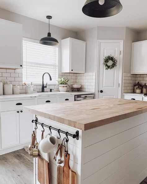 A modern farmhouse kitchen with greige walls and white cabinets features a white island with an ash butcher block countertop. Two black metal pendant lamps hang from the ceiling. The backsplash is of white subway tile...   Image: _littlebitofgrace_ Kitchen With Butcher Block Island, Butcher Block Countertops Kitchen, Two Toned Kitchen Cabinets, Greige Kitchen, Butcher Block Island Kitchen, Kitchen Cabinets Ideas, Butcher Block Kitchen, Mobile Kitchen, Wood Countertop