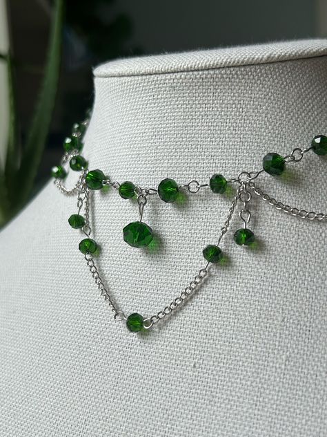 A handmade choker necklace with dark green colored beads/jems that have an emerald coloring. Perfect as a gift or to wear on special occasions or casually to add something to an outfit. nickel free Emerald Handmade Jewelry, Green Jewel Necklace, Emerald Choker Necklace, Green Necklace Aesthetic, Green Necklace Beads, Dark Green Jewelry, Elven Necklace, Emerald Choker, Coquette Jewelry