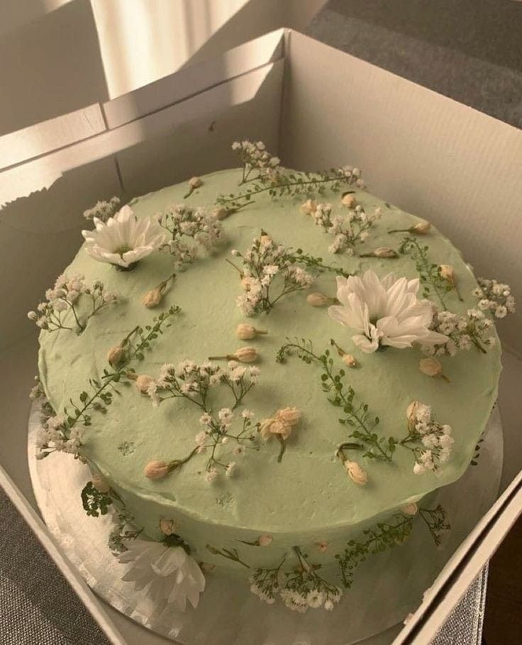 a green cake with white flowers in a box