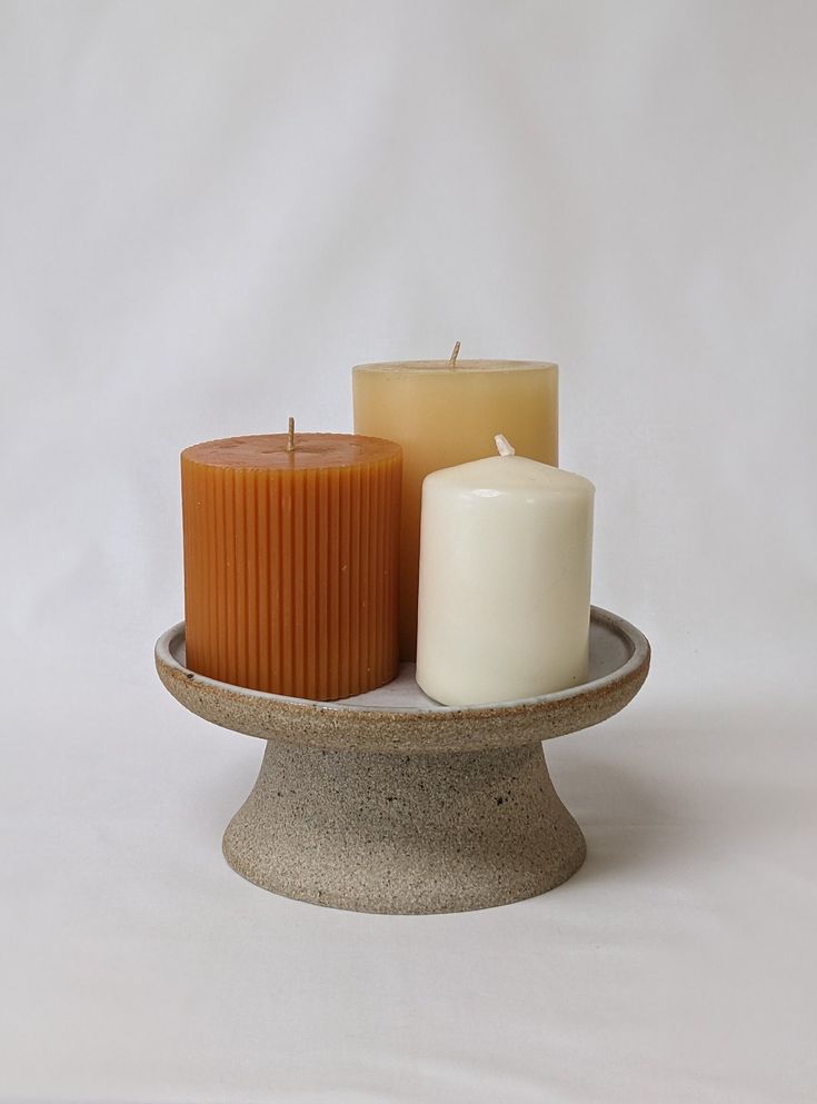 three candles sitting on top of a stone plate with one candle in it's center