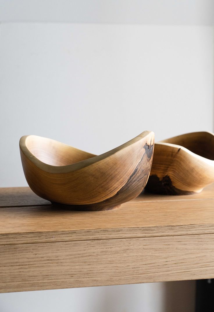 two wooden bowls sitting on top of a table