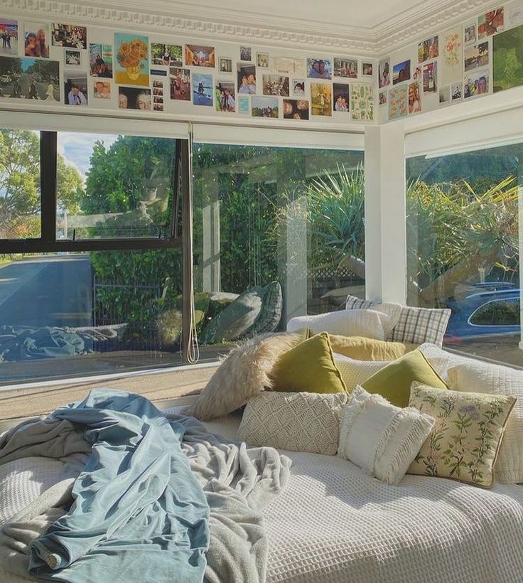 a bed with lots of pillows on top of it in front of a large window