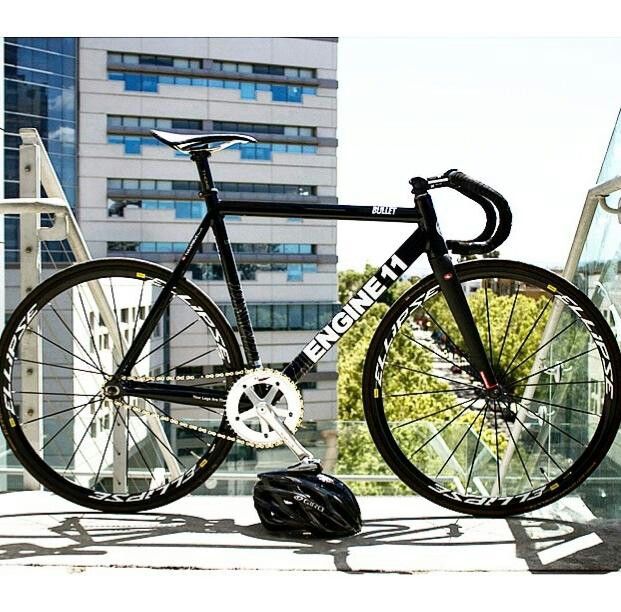 a bicycle parked on the side of a building next to a helmet and some buildings