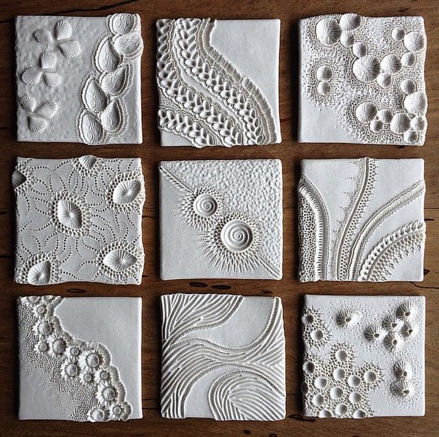 six white tiles with different designs on them sitting on top of a wooden table next to each other